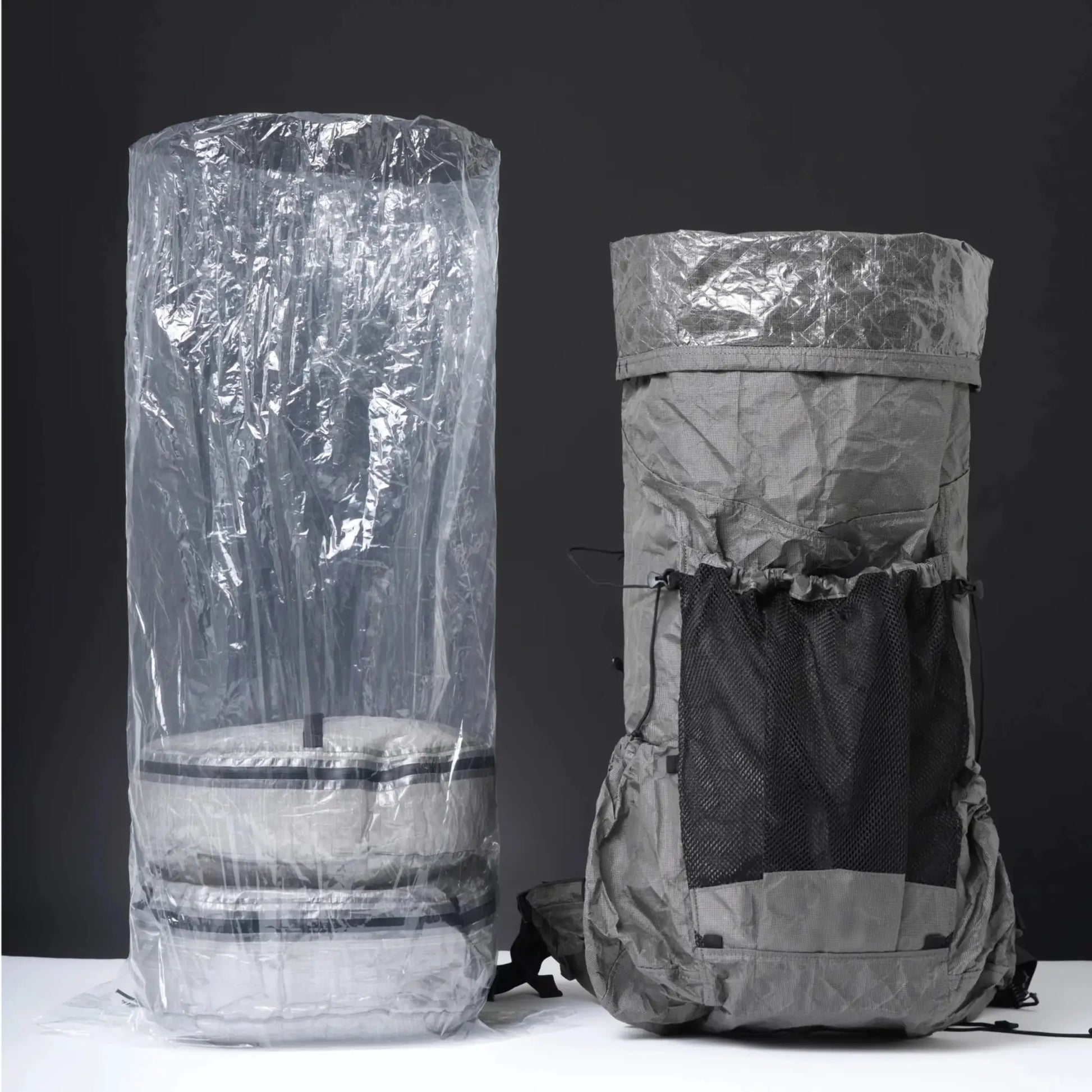 Backpack liner dry bag set: translucent polycro inner bag beside a gray hiking backpack