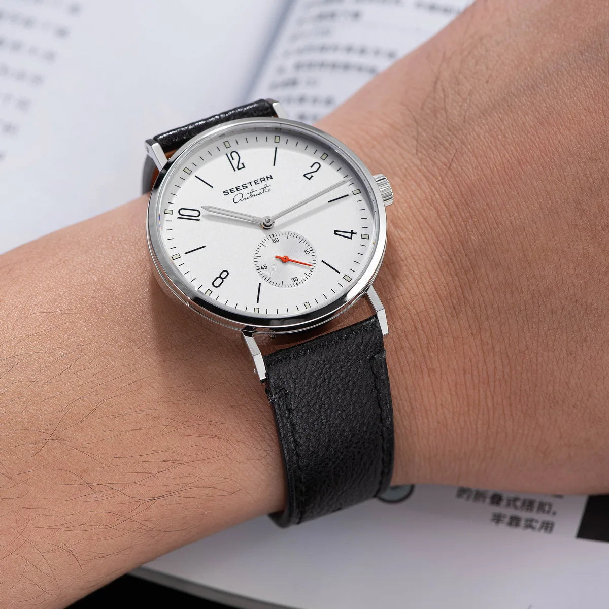 Seestern men's automatic wristwatch with white dial, silver case, and black leather strap.