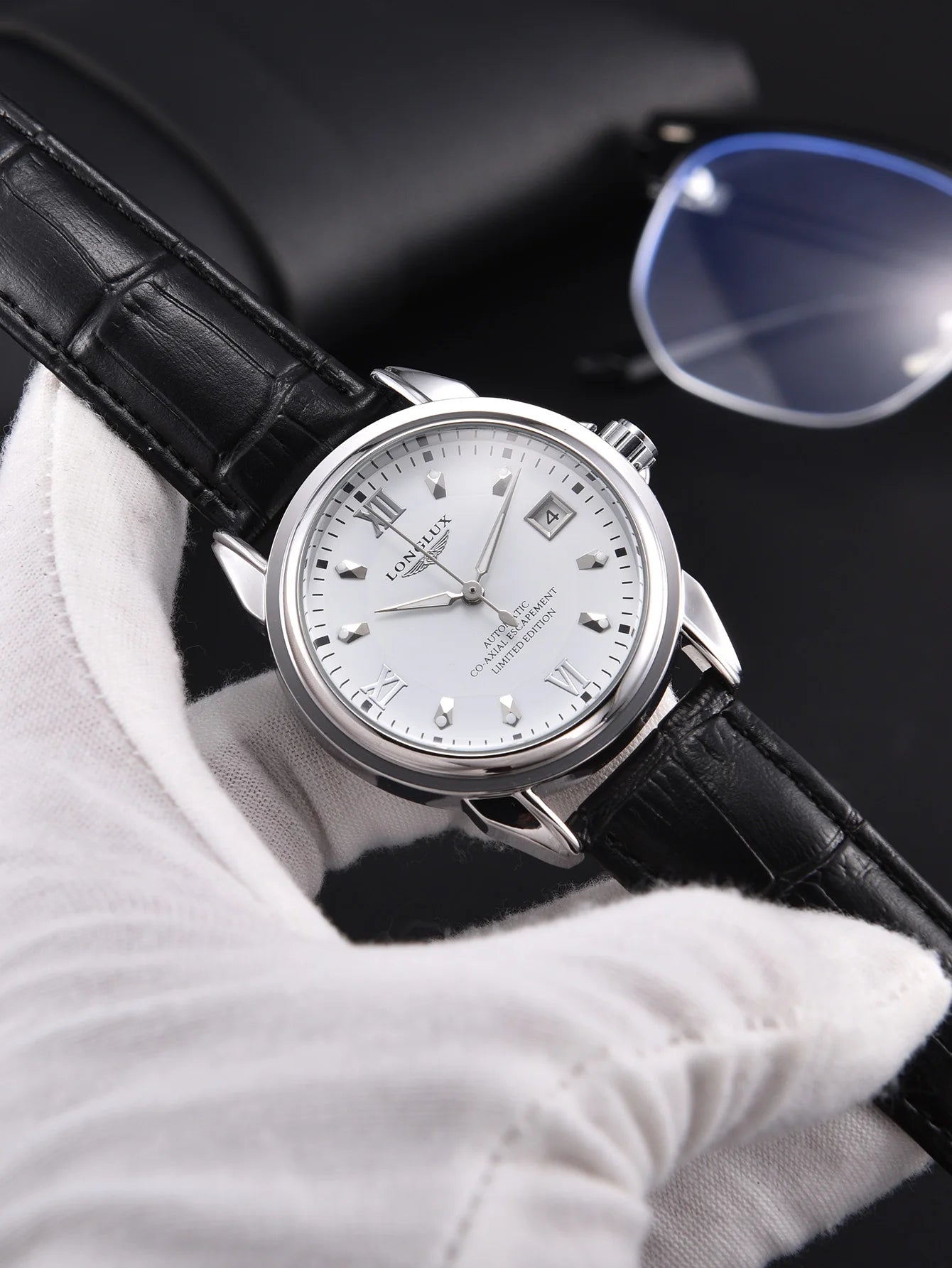 Men's automatic wristwatch with silver case, white dial with date window, and black leather strap.