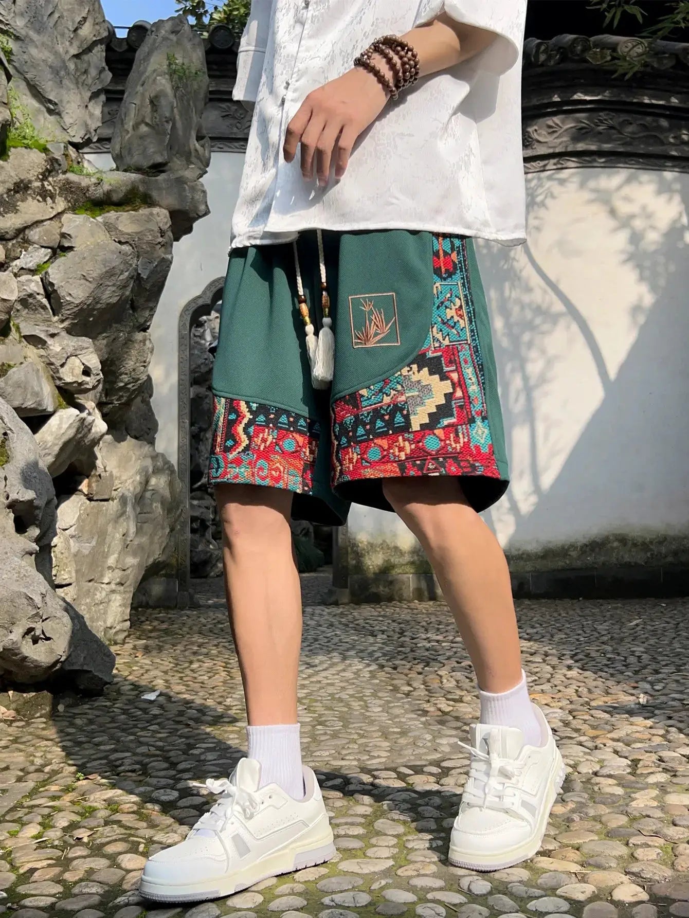 Men's green drawstring shorts with ethnic embroidery panels and pockets