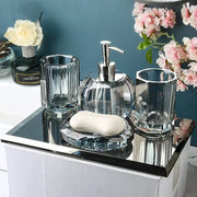 Crystal glass bathroom set with pump dispenser, two tumblers, and soap dish on a mirrored tray
