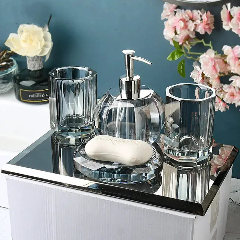 Crystal glass bathroom set with pump dispenser, two tumblers, and soap dish on a mirrored tray