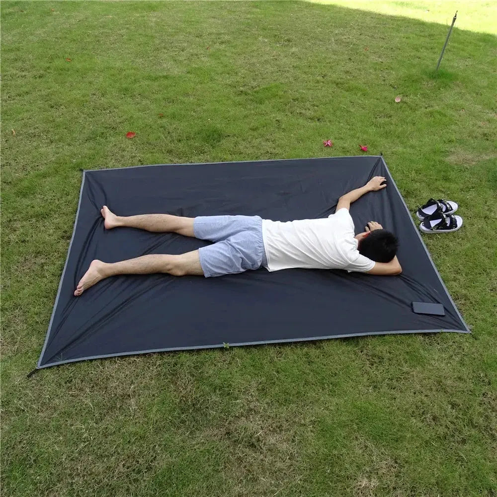Waterproof camping mat by Simples Market, dark gray, ultralight large portable pocket mat laid on grass.