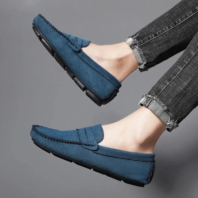 Pair of blue suede men's loafers, slip-on driving shoes with black soles.