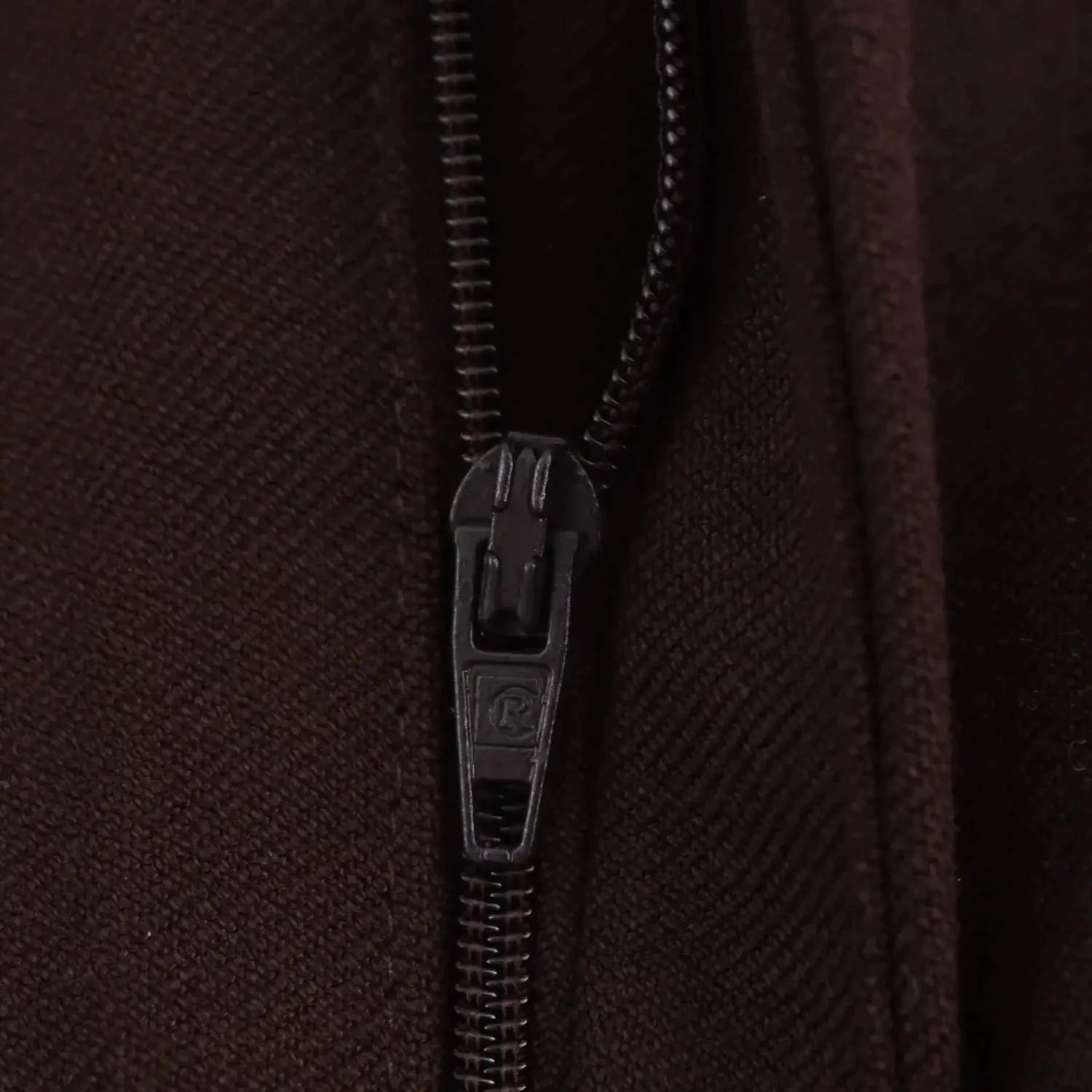 Jacket zipper close-up on dark brown textured fabric.