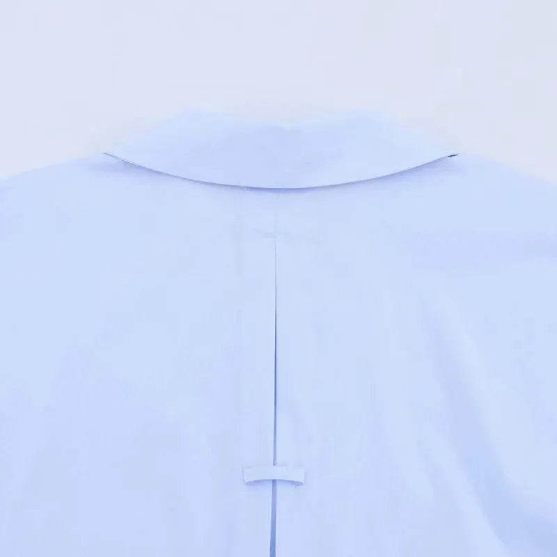 Light blue women's shirt back view with collar, vertical center seam, and small loop tab