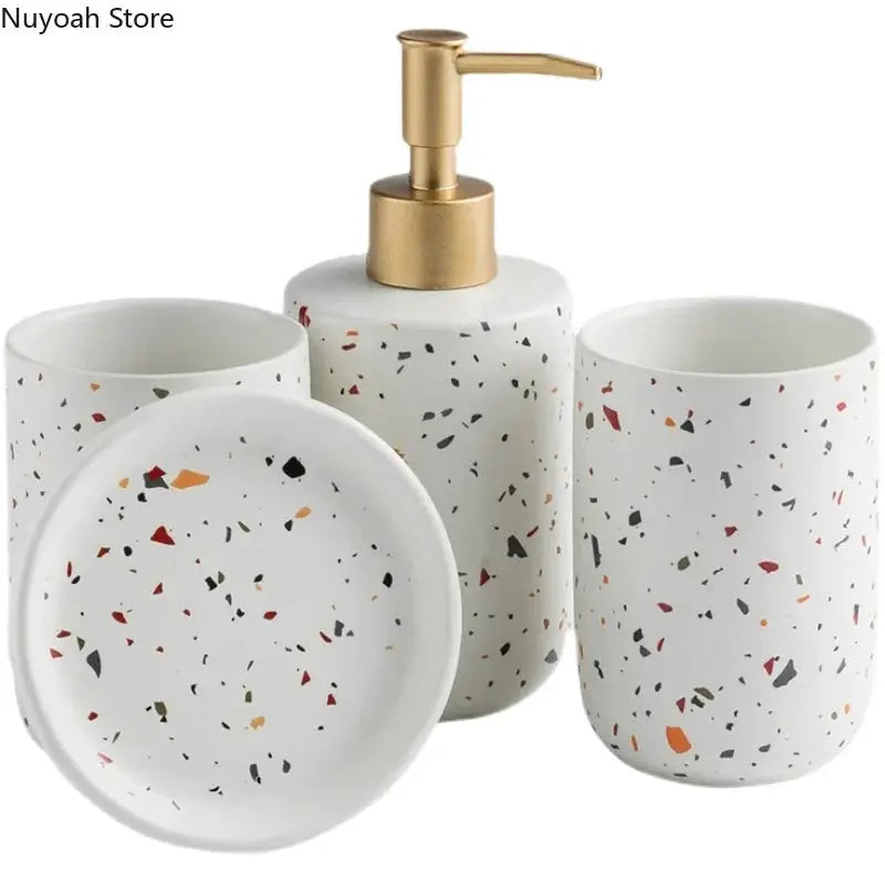 European terrazzo ceramic bathroom set with a gold-pump emulsion bottle, two cups, and a soap dish.