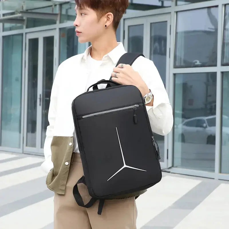 Laptop backpack in black with anti-theft hard-shell design, white geometric logo, front zip pocket and carrying handle.