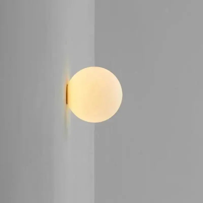 Milky white glass ball wall lamp by Simples Market with warm frosted glow
