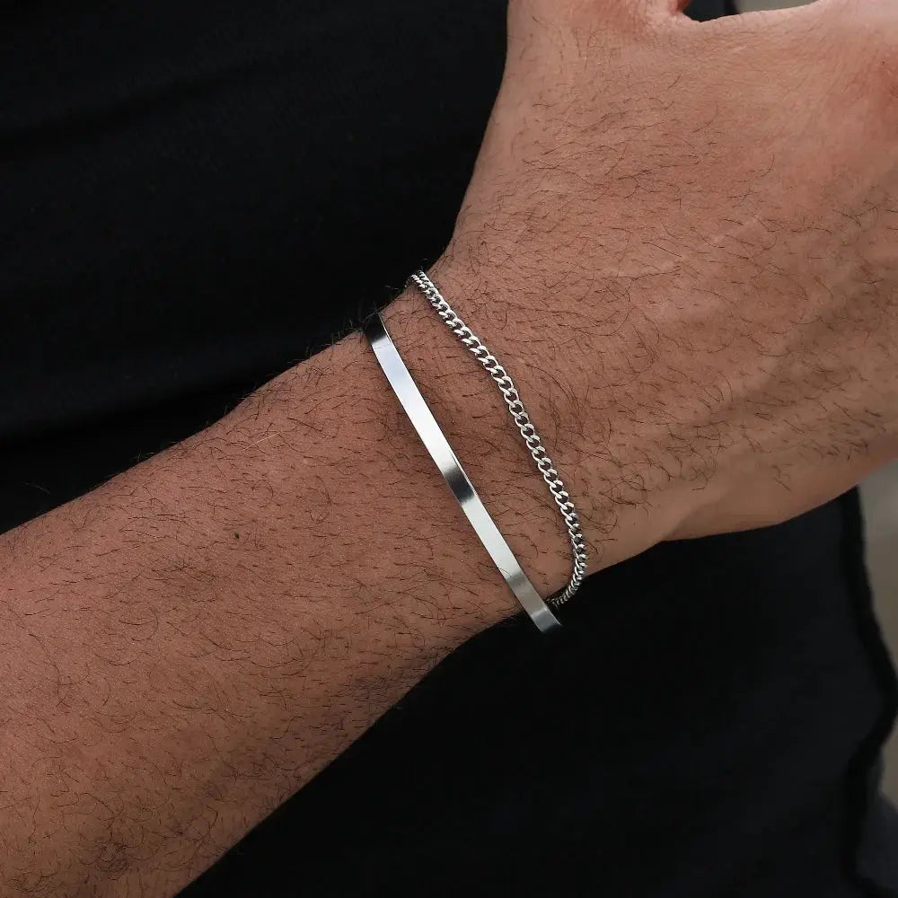 2 silver men's bracelets on wrist: 3mm stainless steel Cuban chain and flat open-band bracelet