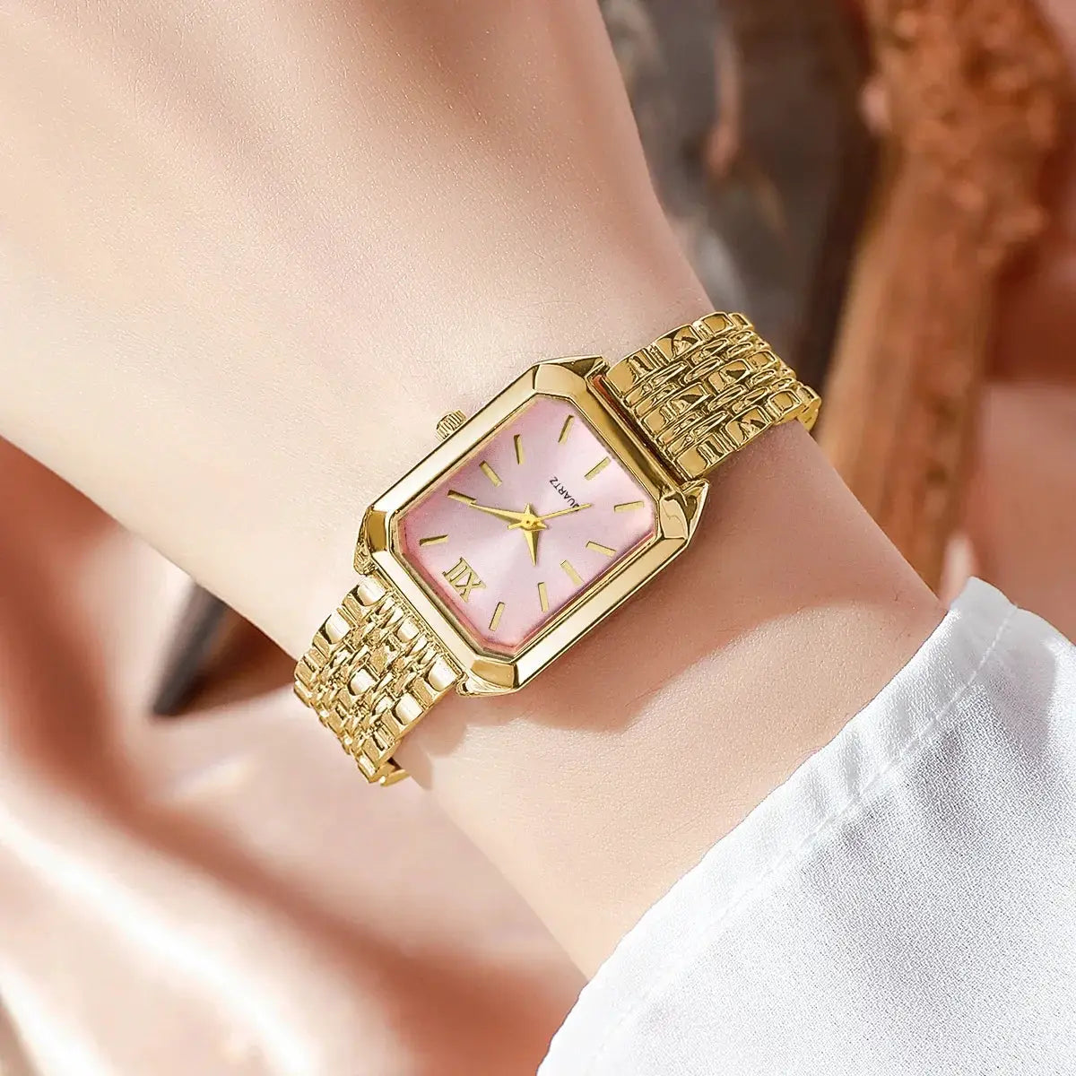 Gold-tone rectangular women's quartz watch with pink dial and linked bracelet.