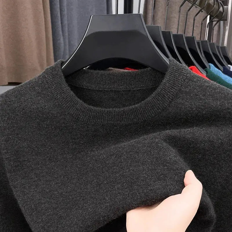 Men's black knitted crewneck sweater on a hanger, long sleeves, among several other colorful sweaters in background