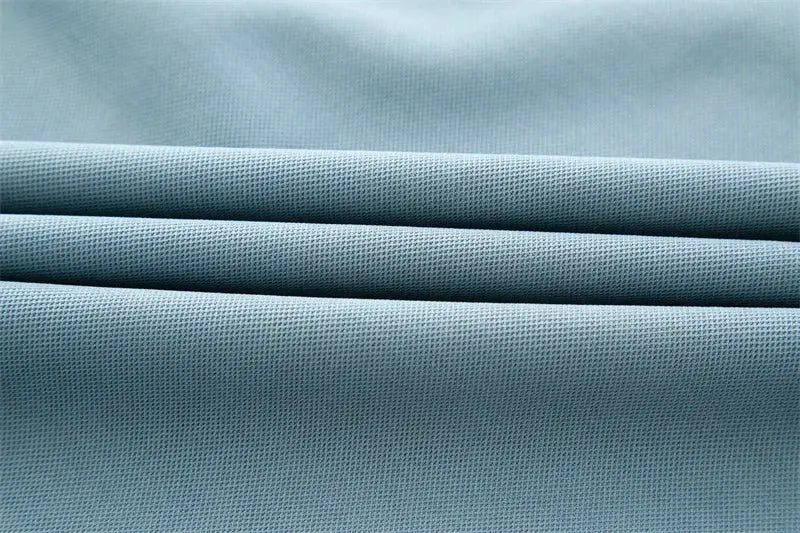 Men's polo shirt fabric close-up in light blue; solid color pique knit texture
