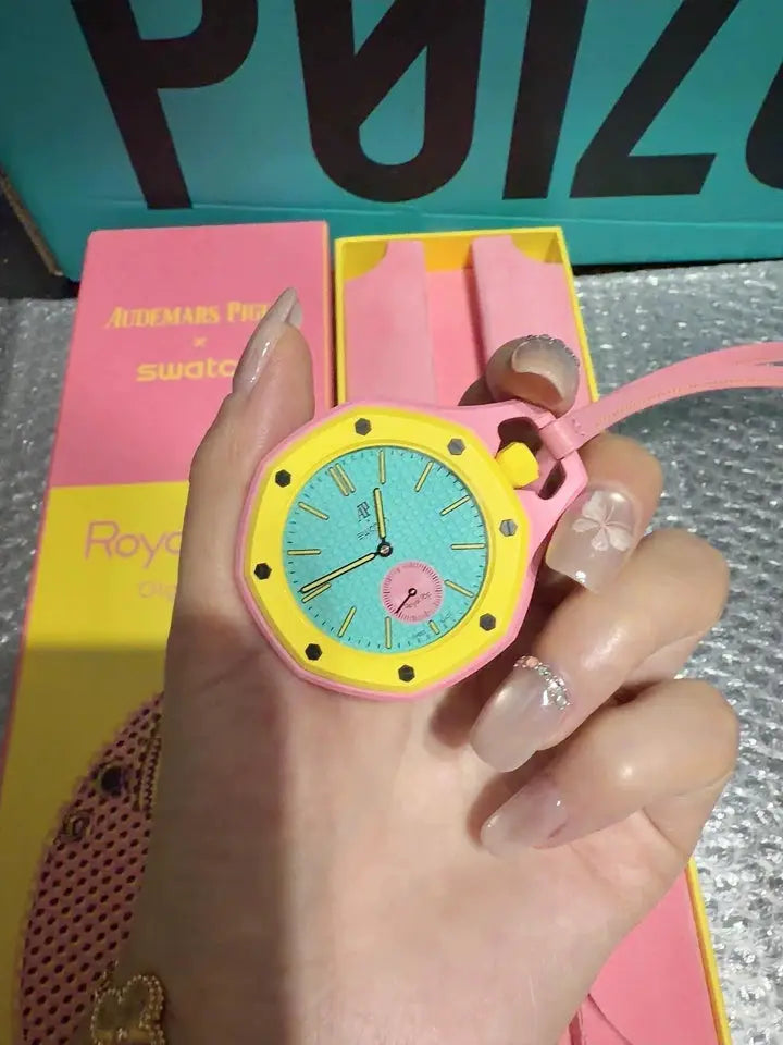 AP Swatch watch with pink case, yellow bezel, turquoise dial, and pink strap.
