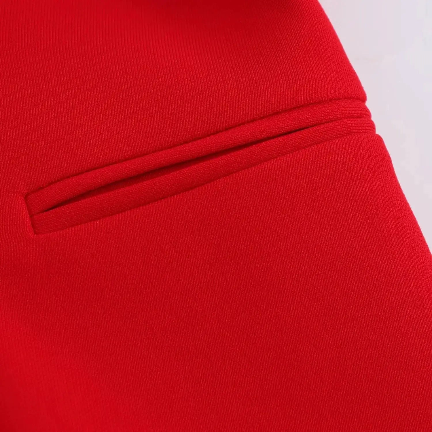 Red blazer close-up showing a double welt pocket detail.