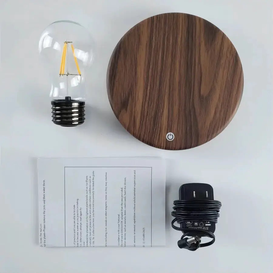 Magnetic levitation lamp with round wood base and glass LED bulb, includes power adapter and manual