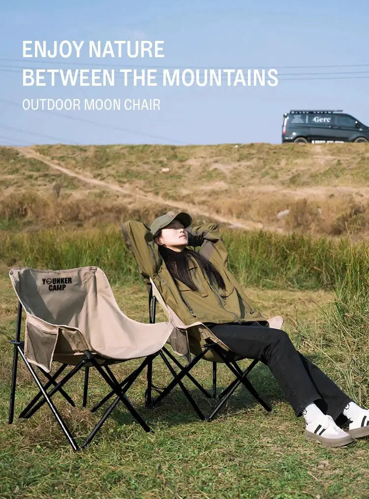 Outdoor moon chairs set in tan fabric with black frames; one person lounges in olive gear beside a second chair.