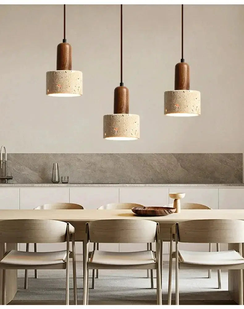 Three wabi-sabi travertine droplight pendants with wood tops over a light dining table