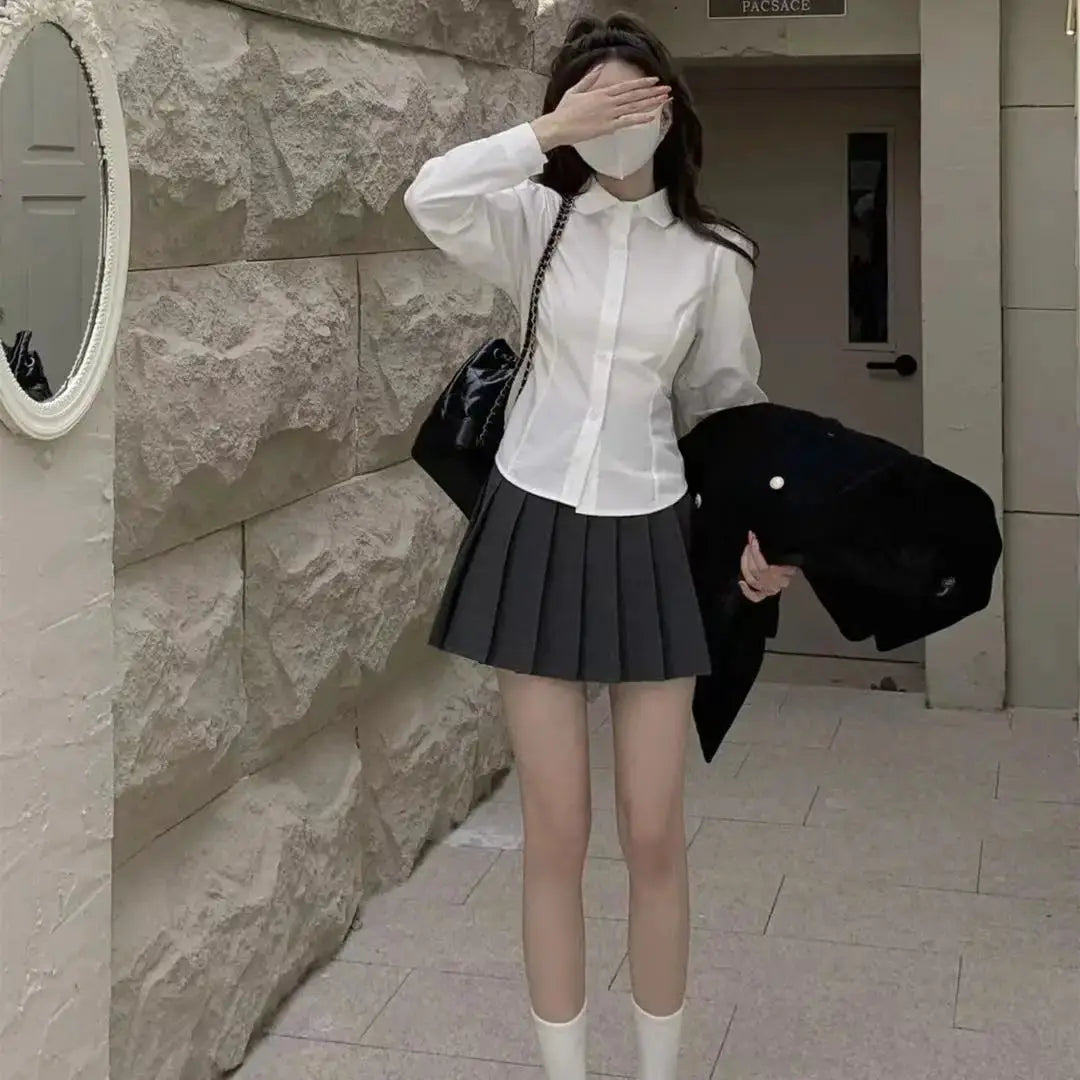 White button-down shirt for women with long sleeves, paired with a gray pleated mini skirt.
