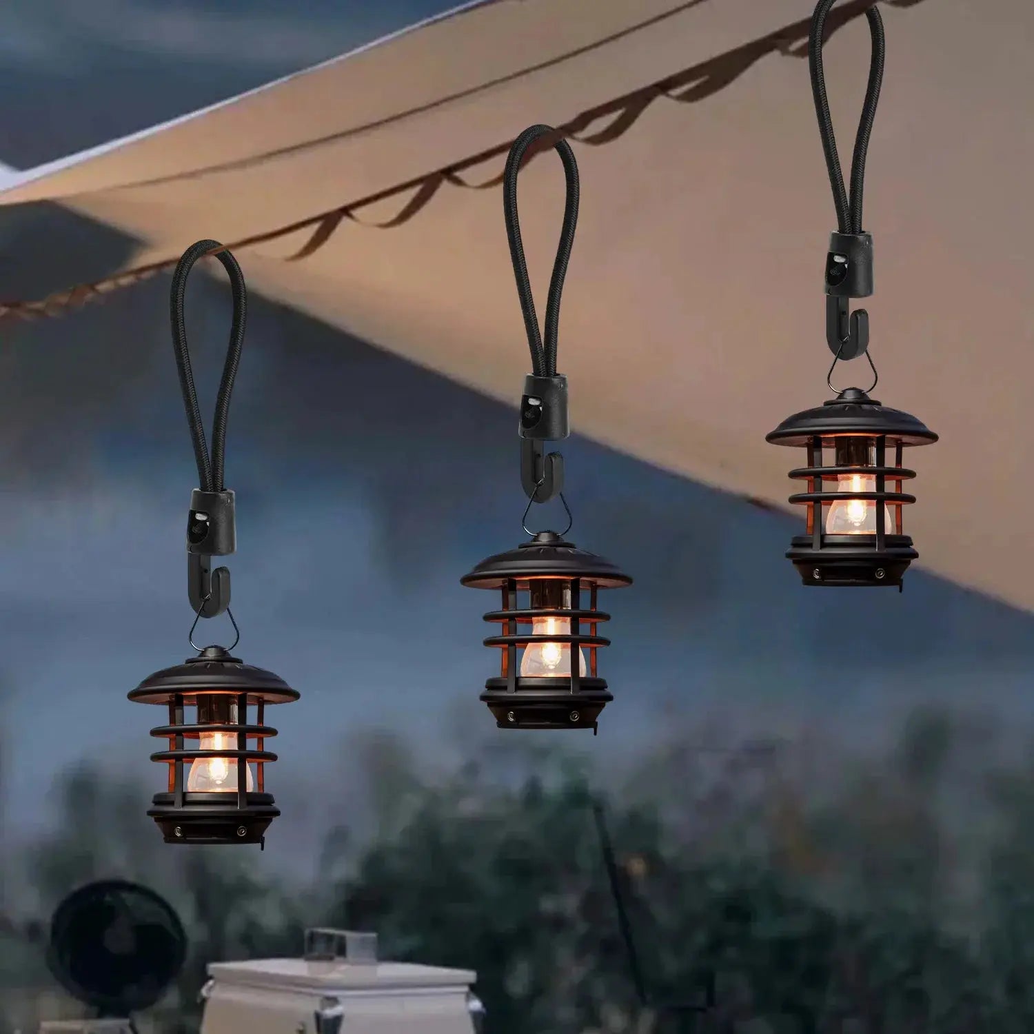 Three black bungee cords with hooks suspending outdoor camping lanterns