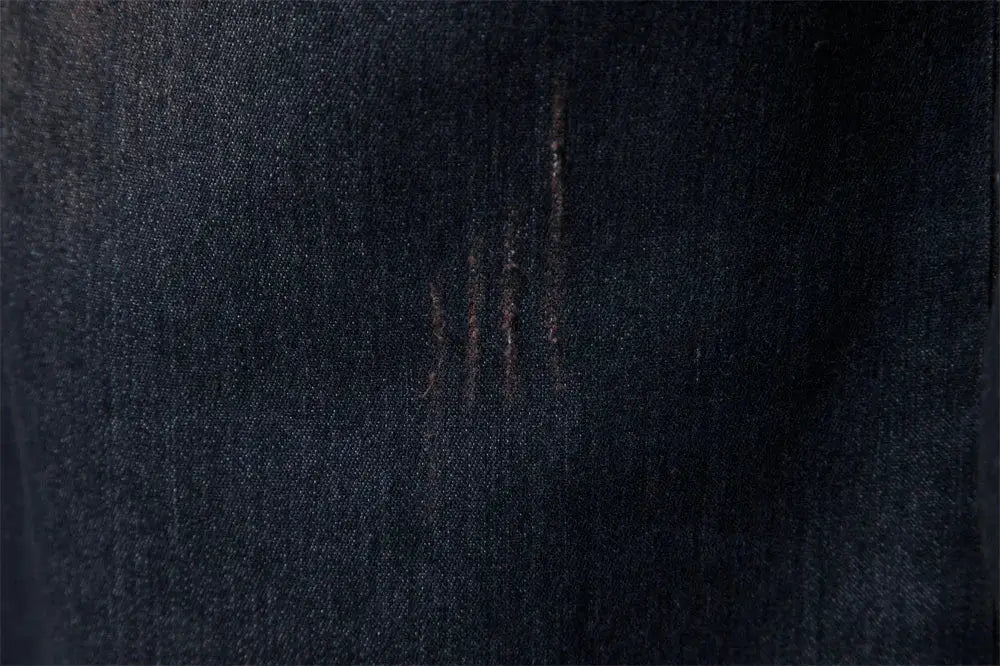 Men's denim shirt fabric close-up in dark indigo cotton with subtle distress marks