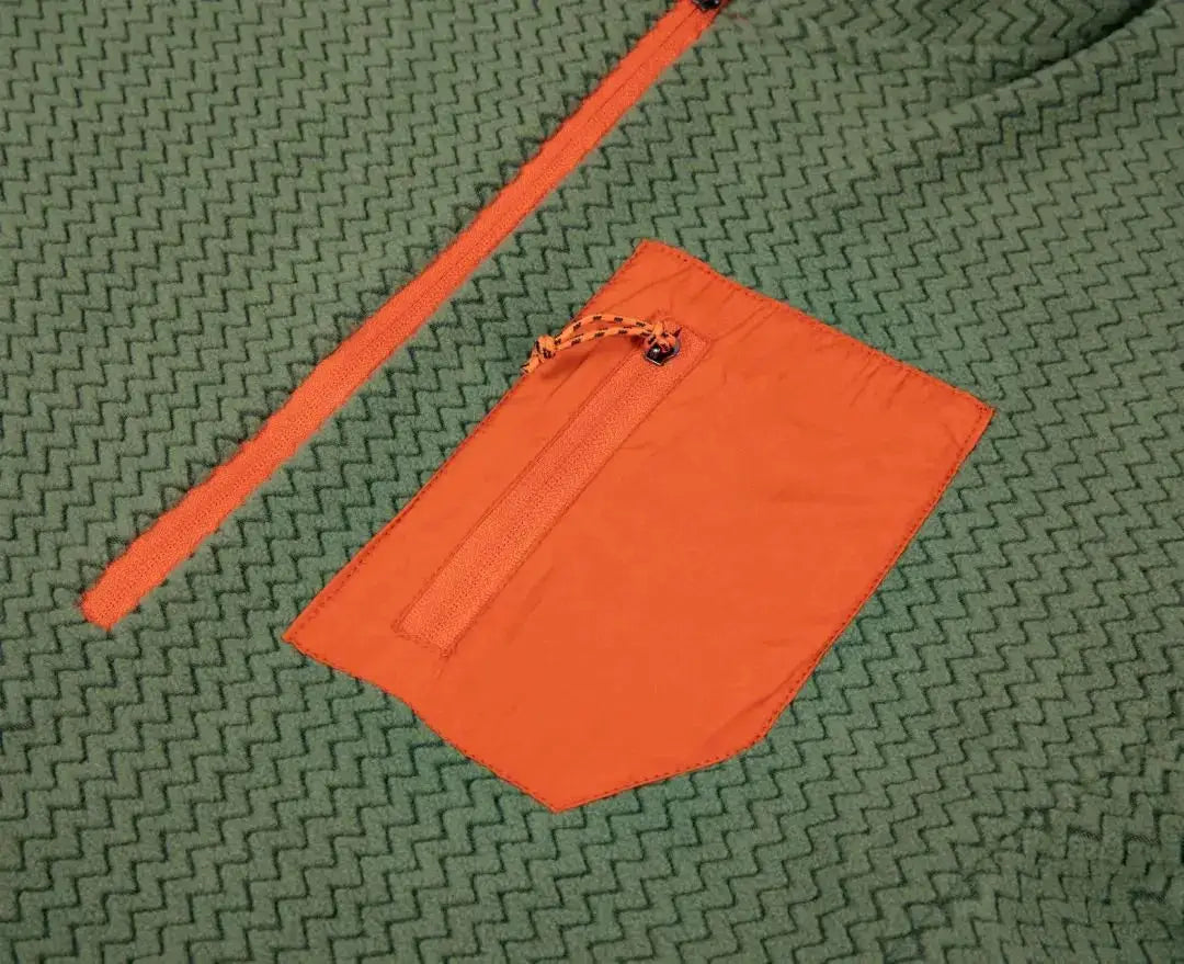 Simples Market fleece sweatshirt with orange zip pocket and drawstring on green textured surface