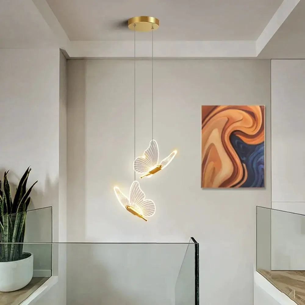 LED butterfly pendant lights, two gold-tone fixtures with white wings, modern indoor decor