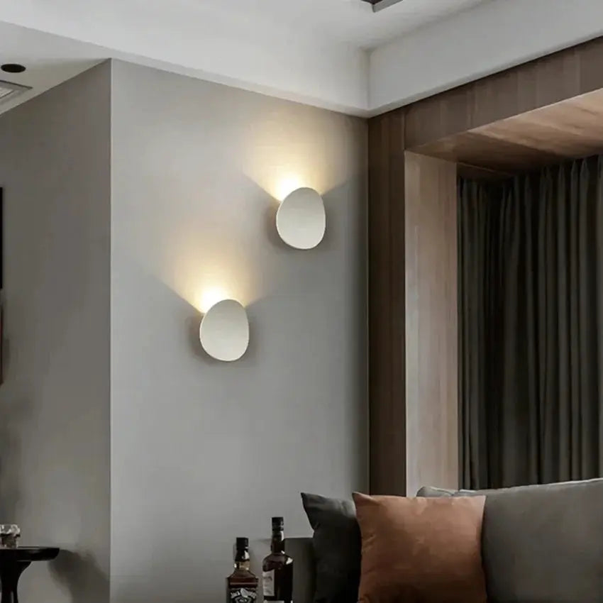 Pair of white round outdoor LED wall lamps, waterproof, with warm ambient light on gray wall