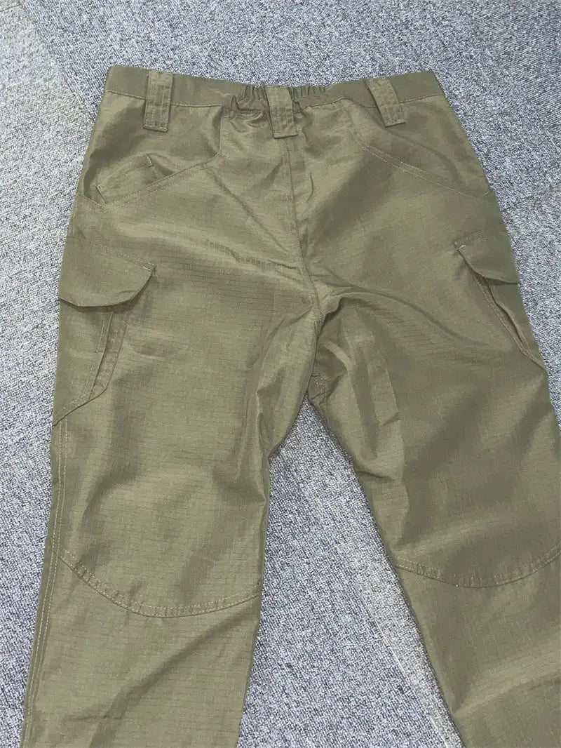 Men's olive green cargo pants with multiple pockets, water-repellent fabric.
