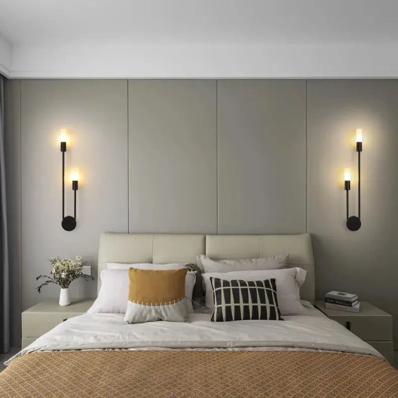 LED black metal wall lamps (two) with warm golden glow flanking a modern bedroom headboard