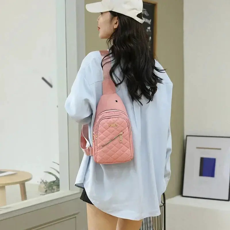 Pink quilted mini backpack, a shoulder bag with gold zipper, worn by a woman in a light blue oversized shirt.