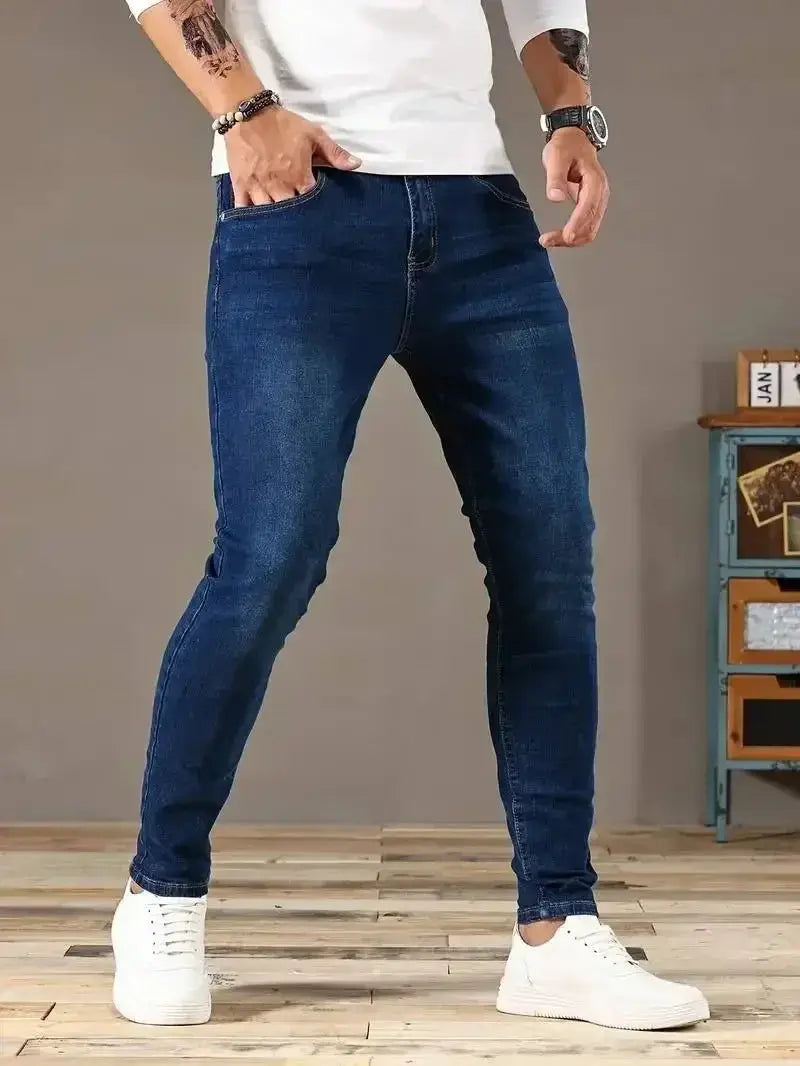 Men's blue denim skinny jeans; slim-fit casual streetwear style with white sneakers