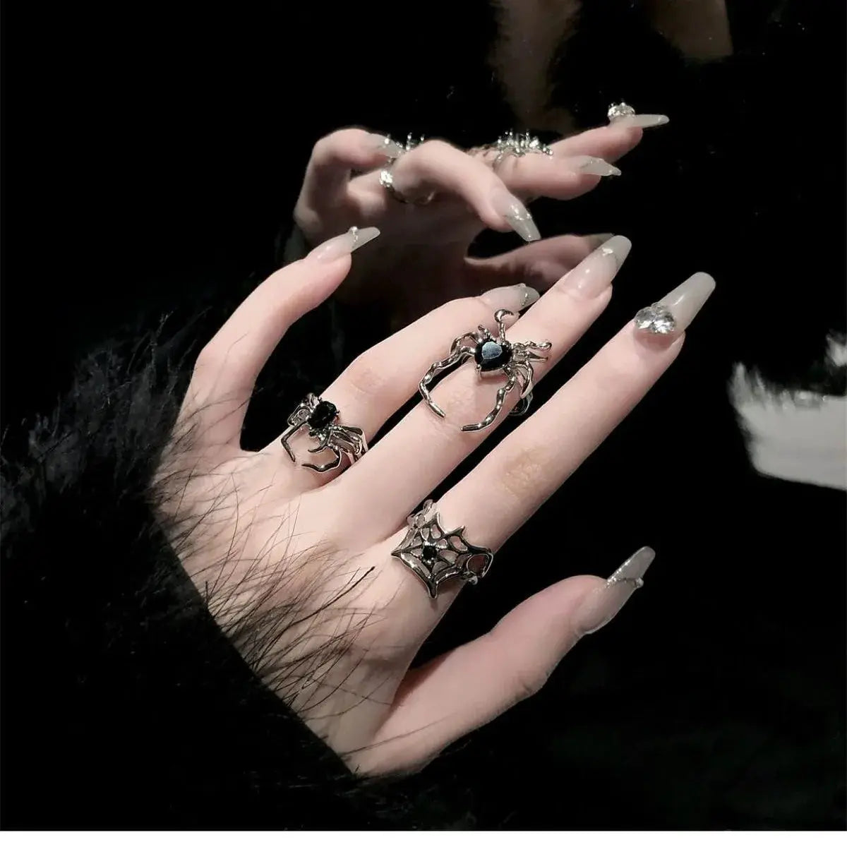 Goth punk open-ring set of several rings on a hand, spider and web motifs with crystal accents and long nails.