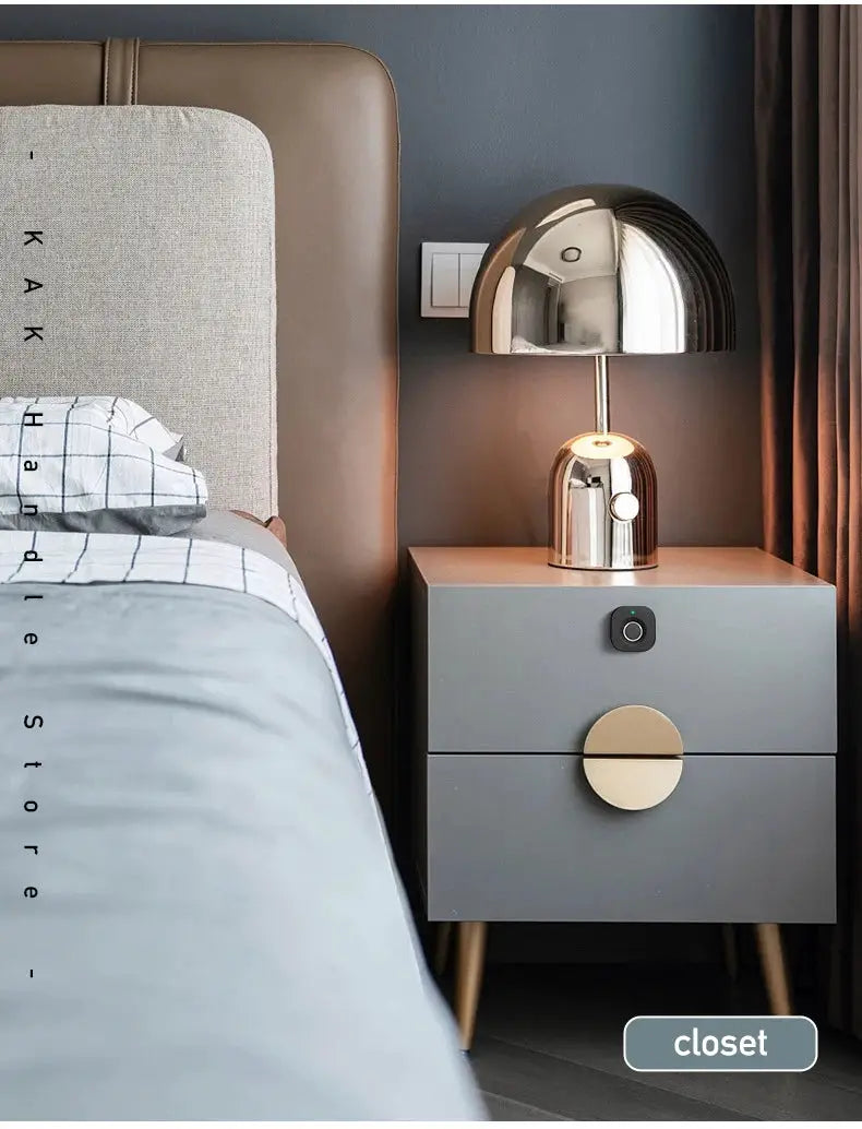 Nightstand with chrome lamp on top; gray two-drawer cabinet with brass round handle