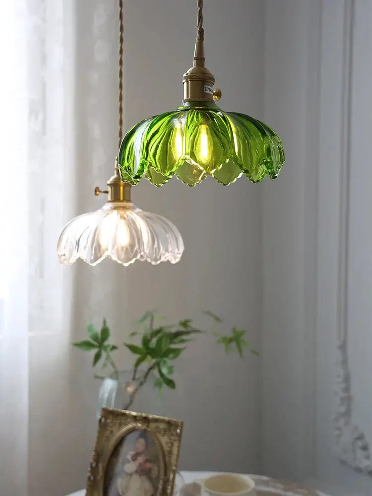 Two vintage glass pendant lights, green and clear with brass fittings and braided cords.