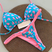 Blue bikini set by Simples Market with pink heart print; triangle top and pink G-string bottom with braided straps.