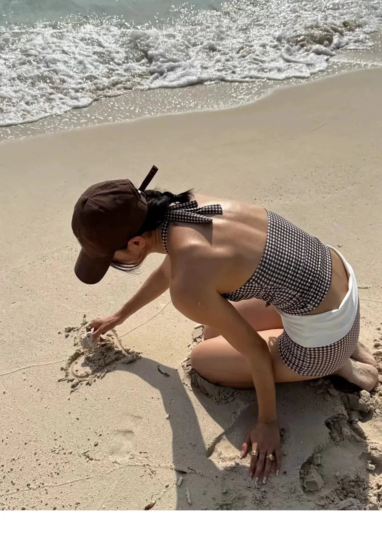 Bikini set by Simples Market; checkered high-waisted bottom with halter top on the beach