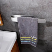 Towel rack, self-adhesive brushed metal, with gray towel hanging in bathroom.