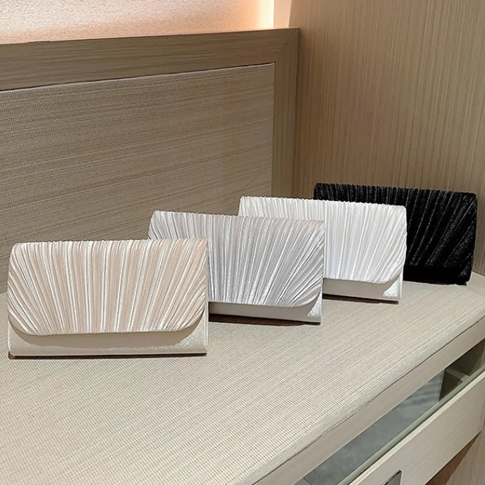 Women evening clutch bags; five pleated fabric clutches in beige, silver, white and black on display