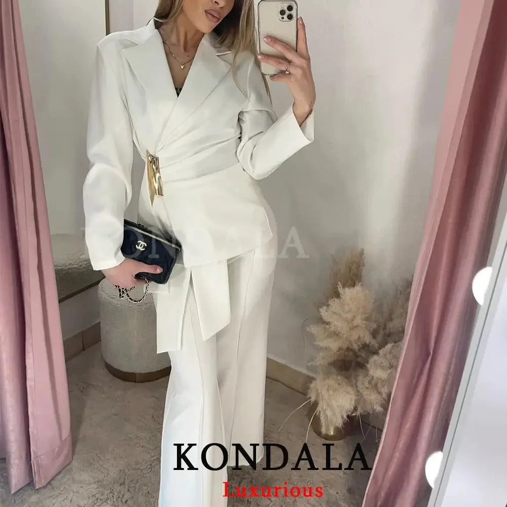 KONDALA 2-piece white blazer suit with wrap belt and wide-leg pants; model holds Chanel clutch