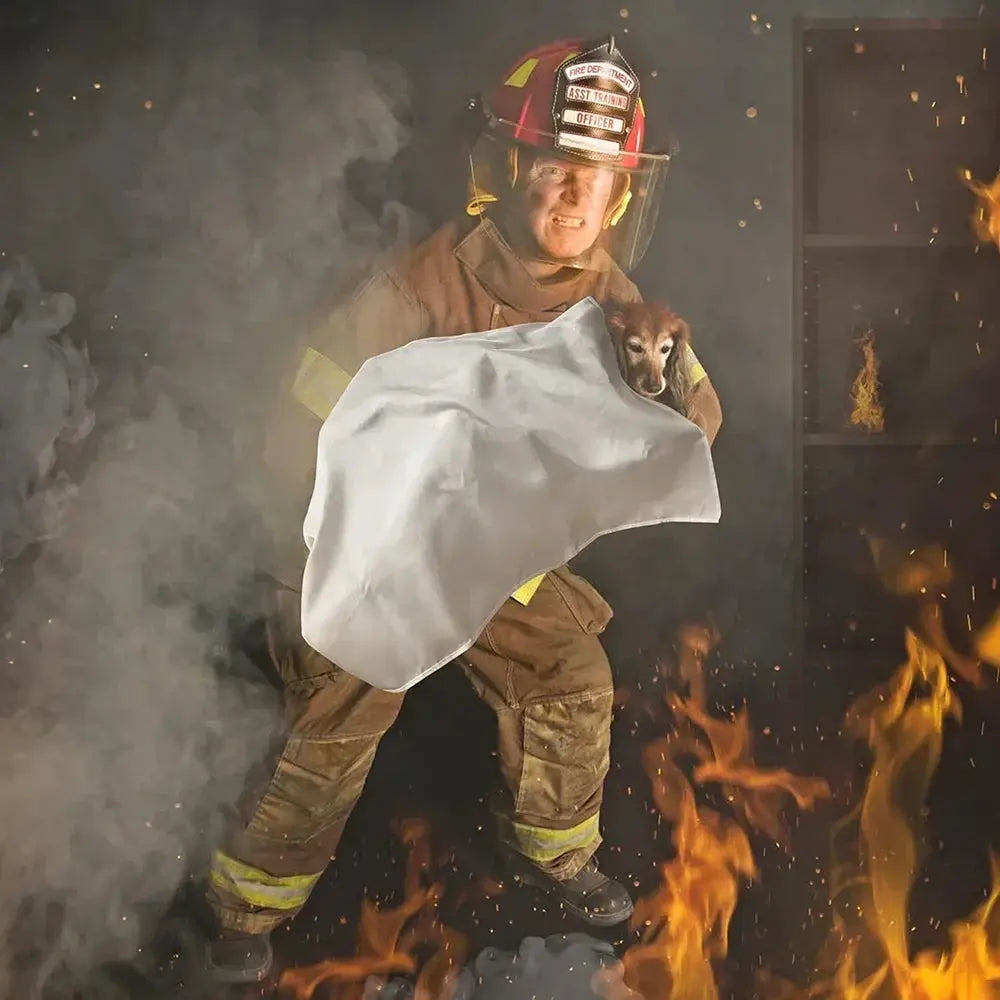 Emergency fire blanket by Simples Market, white fiberglass flame-retardant blanket shielding a small dog from flames.