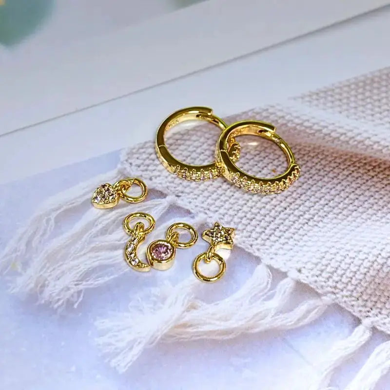 Gold-tone hoop earrings with pave crystals and seven charm pendants (moon, star, heart) in a seven-piece set