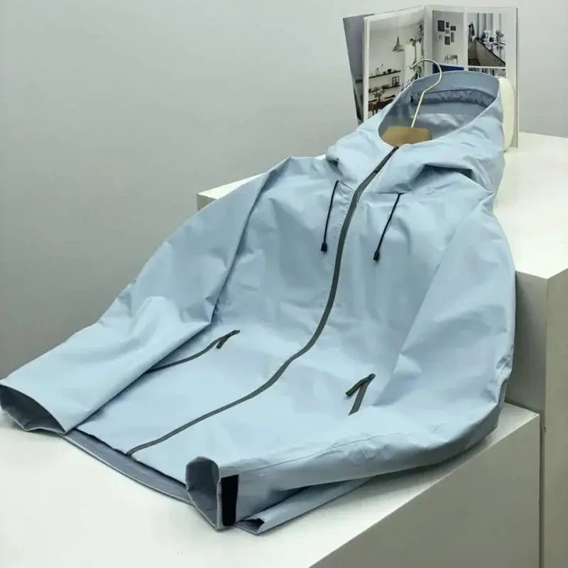 Men's light blue windproof soft-shell jacket with hood, drawstrings, and full-zip