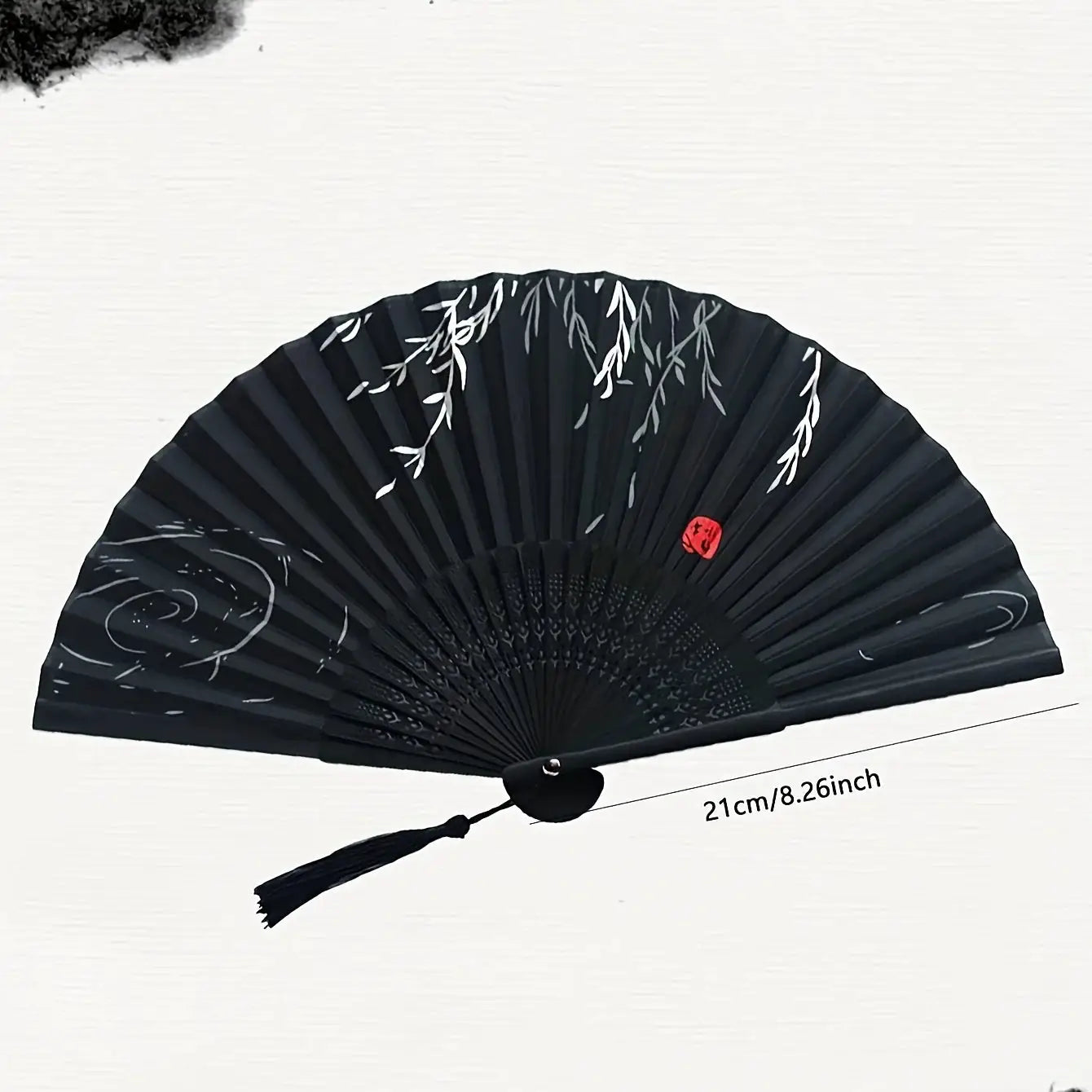 Black bamboo hand folding fan with white leaf pattern and red seal, 21 cm.