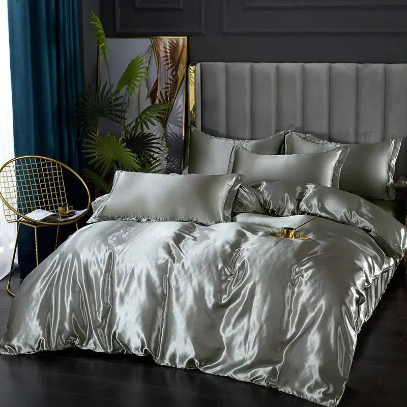 Silk satin bedding set in silver-gray on a bed with a tufted headboard; includes duvet cover, sheet and pillowcases