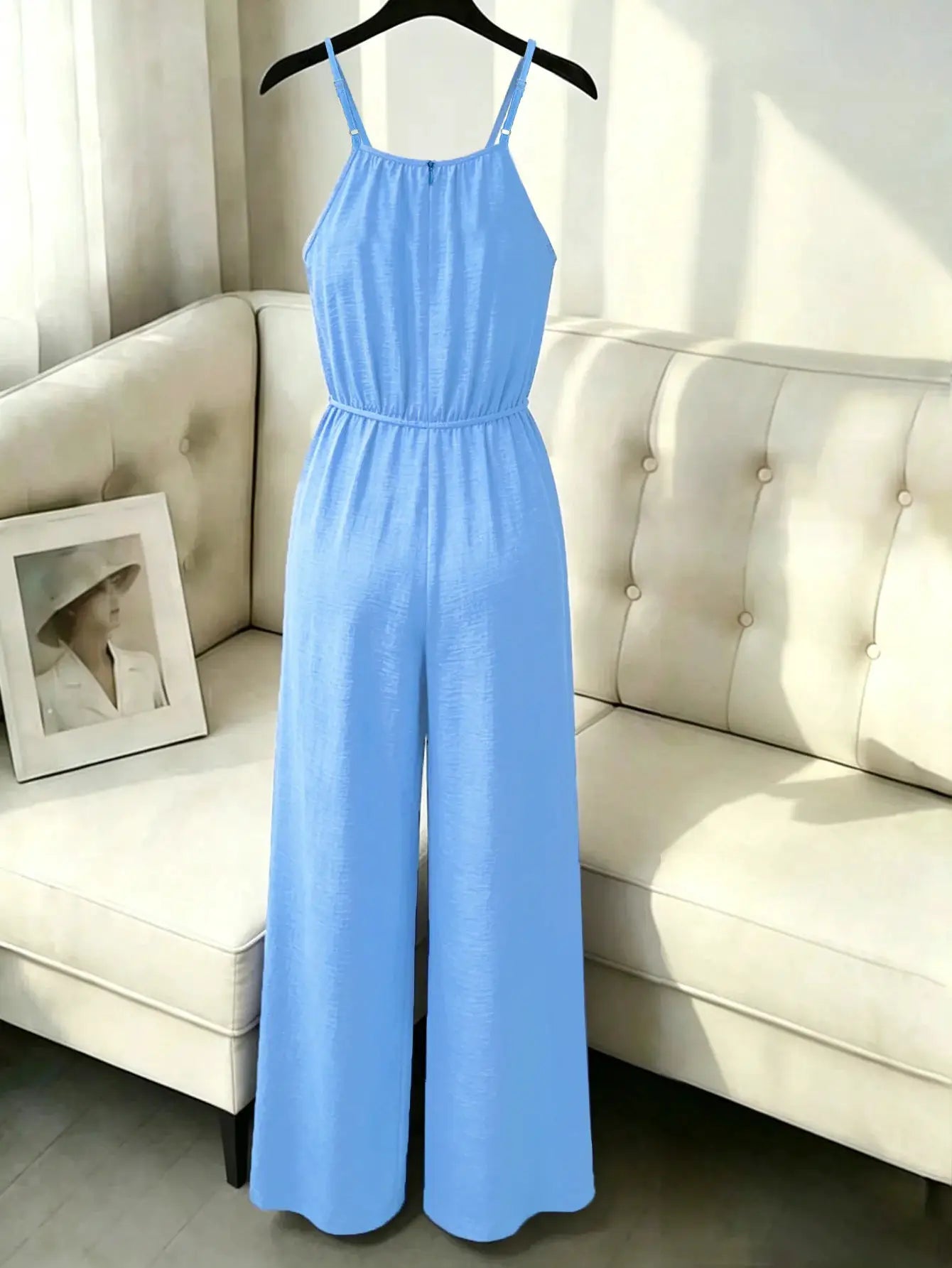 Women's blue sleeveless suspender jumpsuit with gathered waist and wide-leg pants.