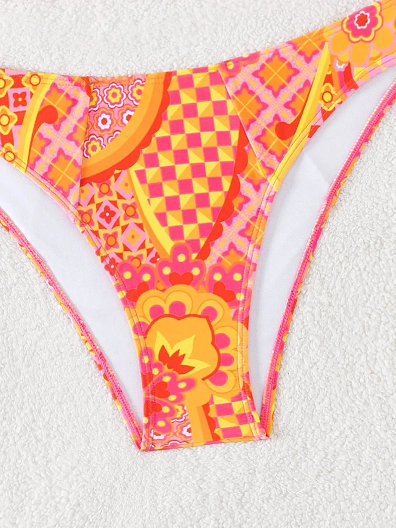 Triangle bikini bottoms in bright pink, orange and yellow floral print with geometric accents; Brazilian cut.