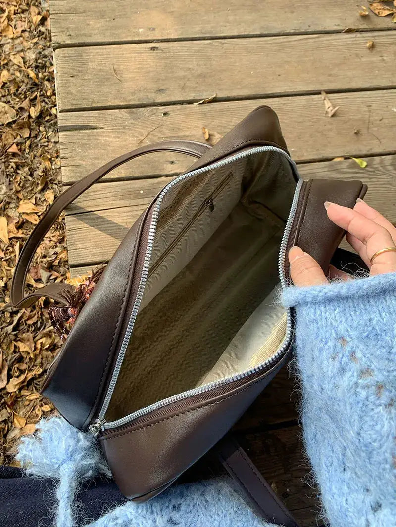 Brown leather-like single-shoulder tote bag with zipper, large capacity and beige lining.