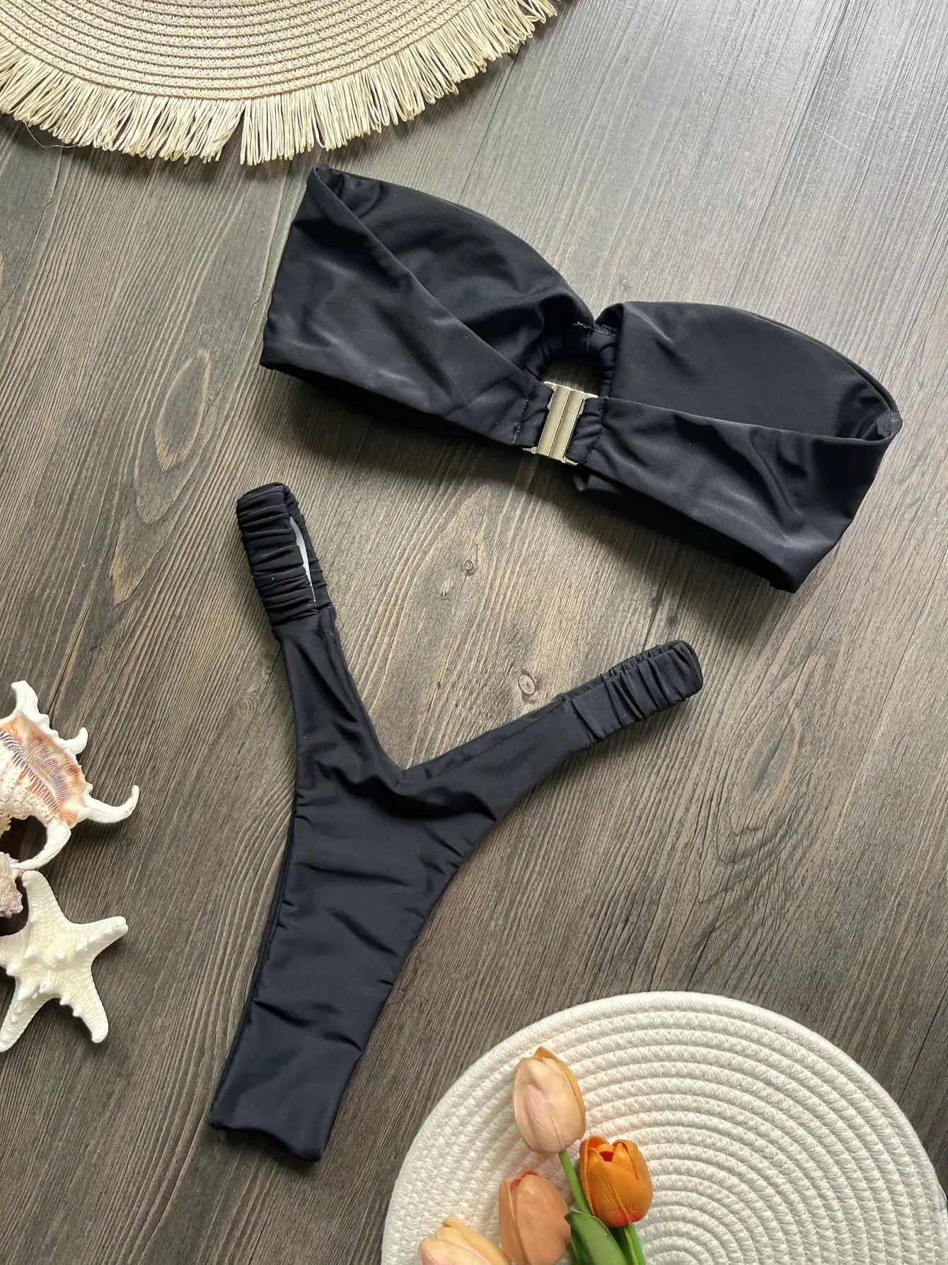 Micro bikini set in black with bandeau top and thong-style bottom, gold clasp detail.