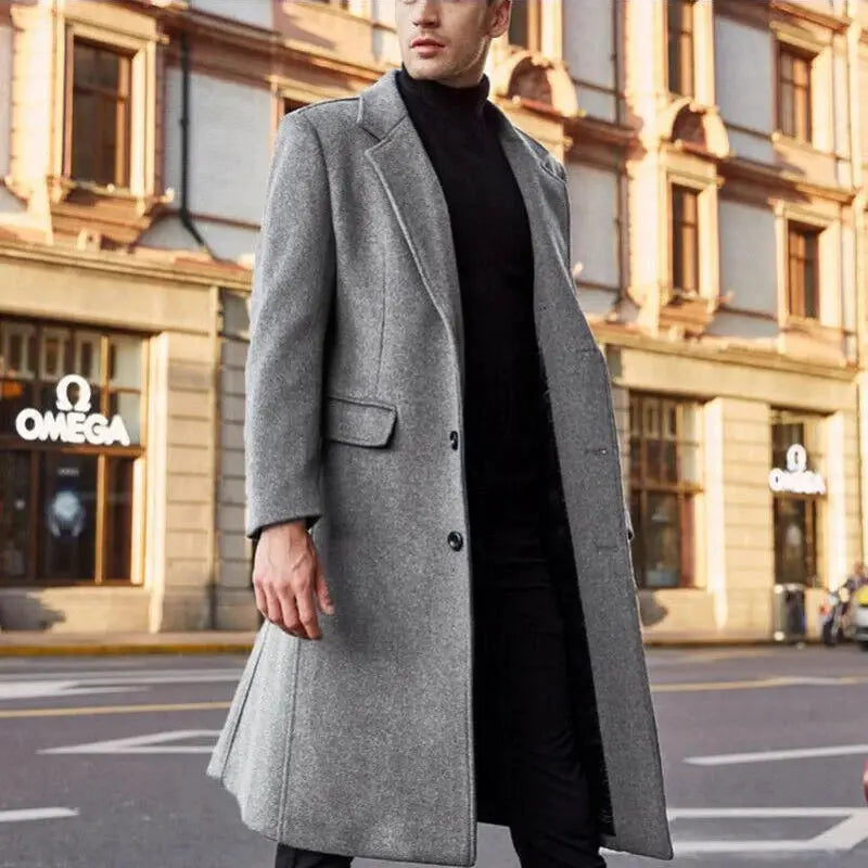 Simples Market men's grey wool coat, long trench-style overcoat worn over a black turtleneck on a city street.